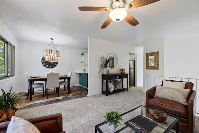 living room with ceiling fan with notable chandelier, carpet, and a textured ceiling