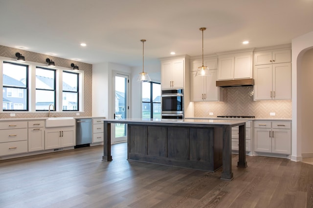 kitchen featuring a center island, dark hardwood / wood-style flooring, stainless steel appliances, sink, and hanging light fixtures