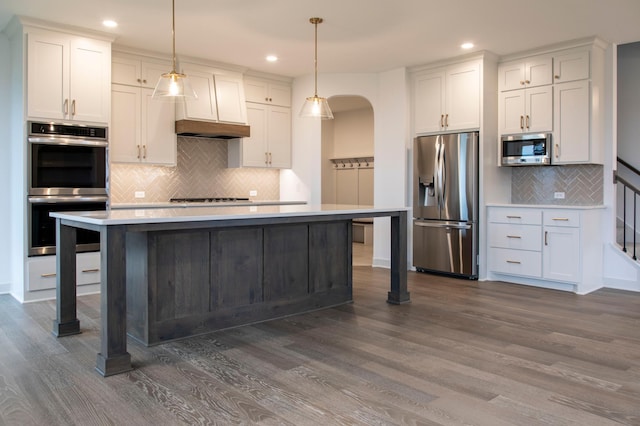 kitchen featuring hanging light fixtures, white cabinets, appliances with stainless steel finishes, and dark wood-type flooring