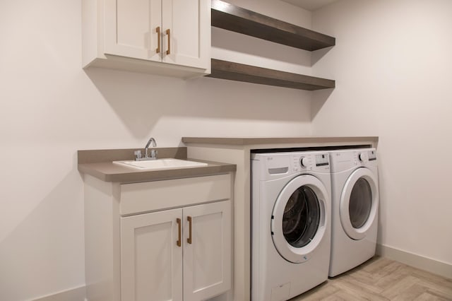 laundry room with light parquet floors, sink, washing machine and clothes dryer, and cabinets