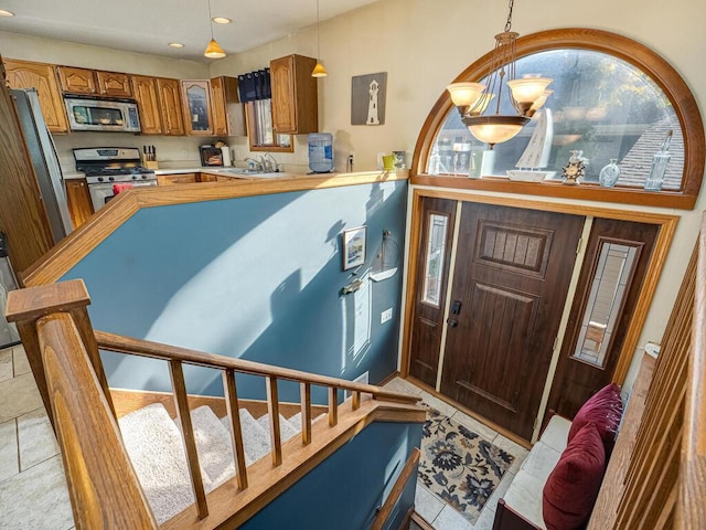 foyer entrance with light tile patterned floors, plenty of natural light, sink, and a chandelier