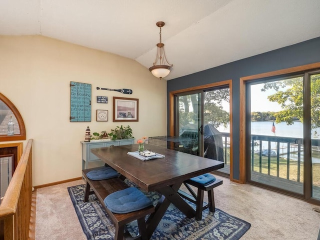 carpeted dining room featuring vaulted ceiling, a water view, and a healthy amount of sunlight