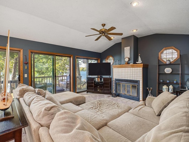 living room featuring ceiling fan, a textured ceiling, light carpet, a fireplace, and vaulted ceiling