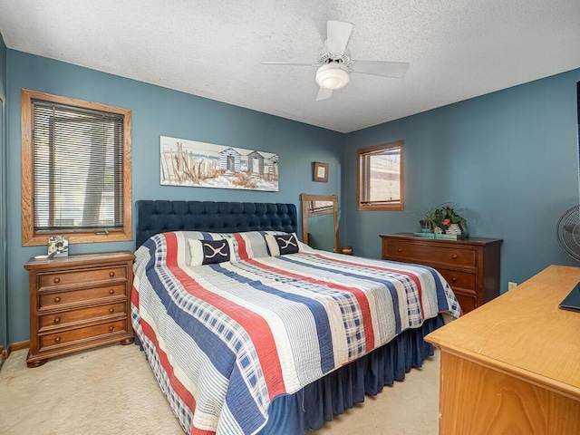 bedroom with light colored carpet, a ceiling fan, multiple windows, and a textured ceiling
