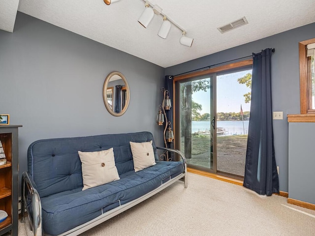 living room with track lighting, a textured ceiling, carpet flooring, and a water view