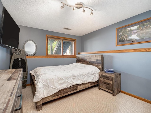 carpeted bedroom with baseboards, visible vents, and a textured ceiling