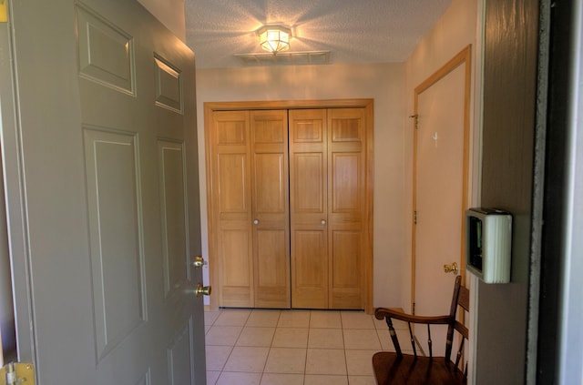 entryway with light tile patterned floors and a textured ceiling