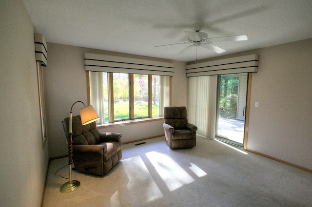 living area featuring a textured ceiling, ceiling fan, and light carpet