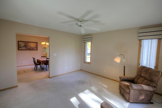 sitting room with ceiling fan with notable chandelier and light colored carpet