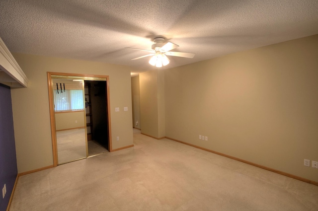 unfurnished bedroom with a textured ceiling, carpet floors, a closet, and ceiling fan