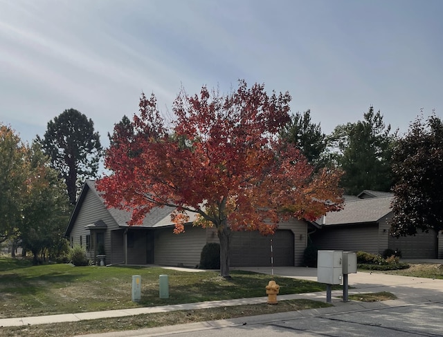 view of front of house with a front yard, concrete driveway, and a garage