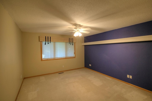 carpeted spare room featuring visible vents, a textured ceiling, baseboards, and ceiling fan