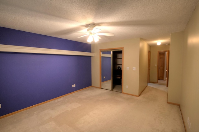 unfurnished bedroom with a closet, a textured ceiling, baseboards, a ceiling fan, and light colored carpet