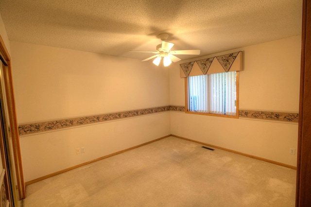 carpeted empty room featuring baseboards, visible vents, ceiling fan, and a textured ceiling