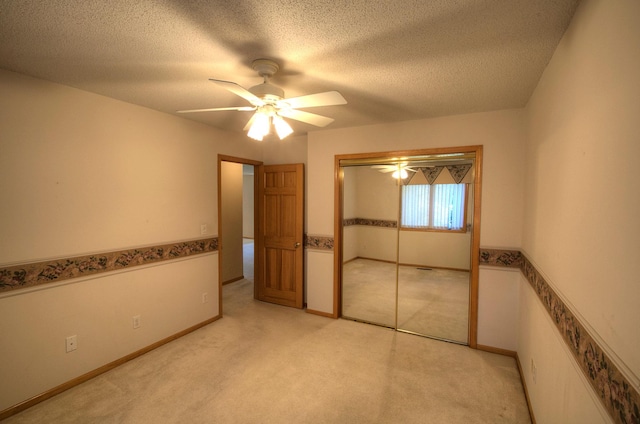 unfurnished bedroom with light colored carpet, baseboards, a textured ceiling, ceiling fan, and a closet