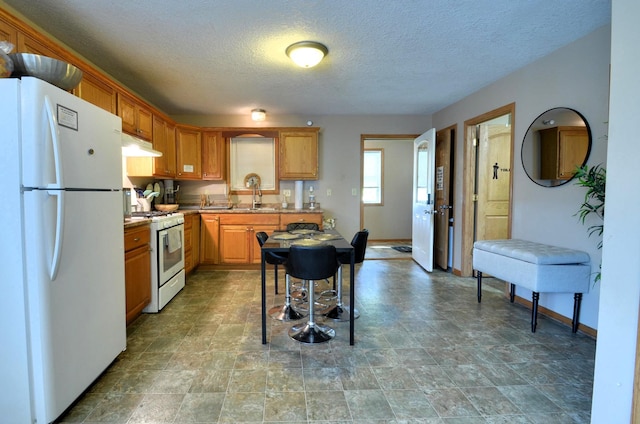 kitchen featuring white appliances, a textured ceiling, and sink