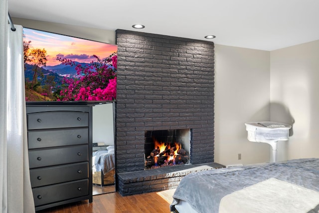 bedroom featuring hardwood / wood-style flooring and a brick fireplace