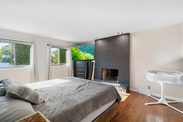 bedroom with hardwood / wood-style flooring and a fireplace