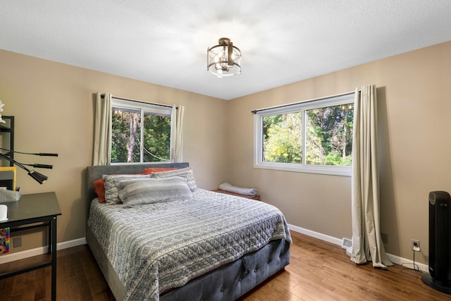 bedroom featuring a chandelier, wood-type flooring, and a textured ceiling