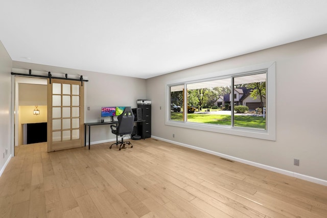 office area featuring a barn door and light hardwood / wood-style floors