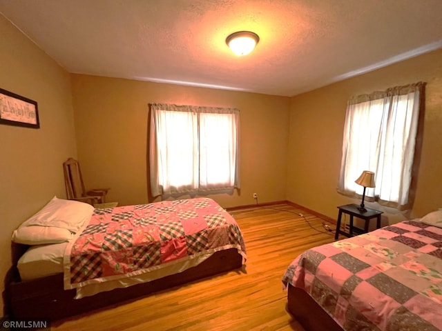 bedroom with light wood-type flooring and a textured ceiling