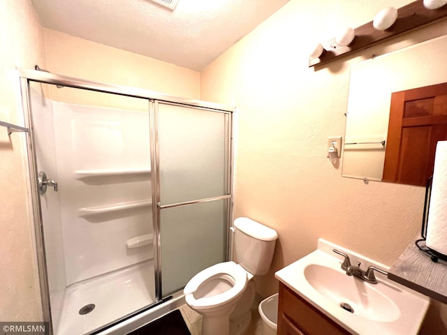 bathroom featuring a textured ceiling, a shower with door, vanity, and toilet