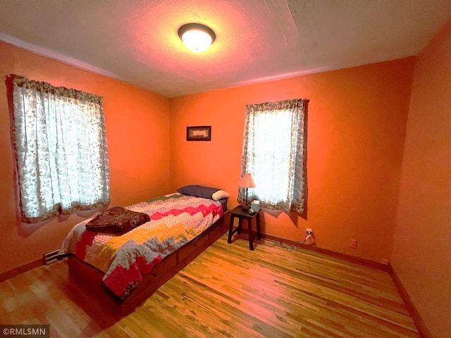 bedroom with hardwood / wood-style flooring and multiple windows