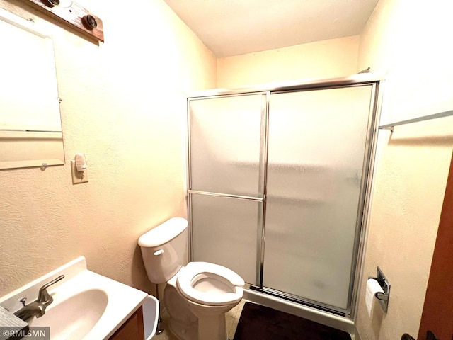 bathroom with an enclosed shower, vanity, and toilet