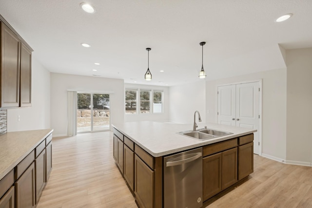 kitchen with sink, hanging light fixtures, light hardwood / wood-style flooring, dishwasher, and an island with sink