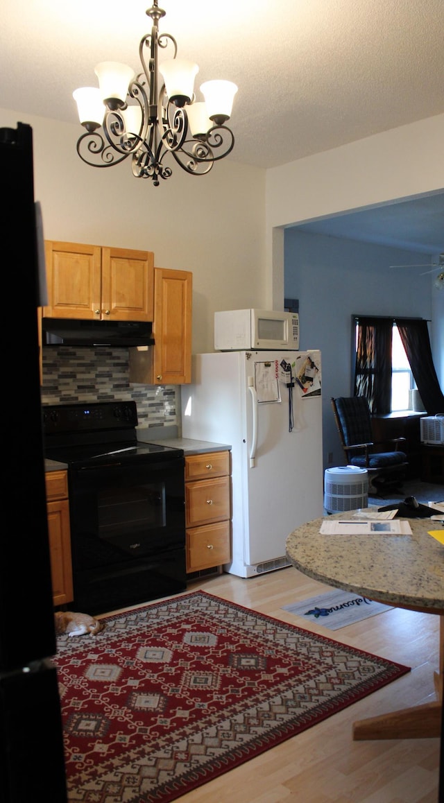 kitchen featuring ceiling fan with notable chandelier, black appliances, light hardwood / wood-style floors, backsplash, and hanging light fixtures