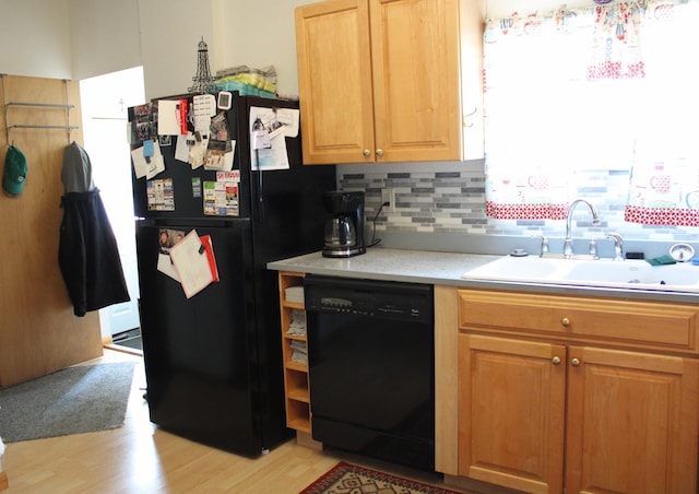 kitchen featuring sink, light hardwood / wood-style floors, tasteful backsplash, and black appliances