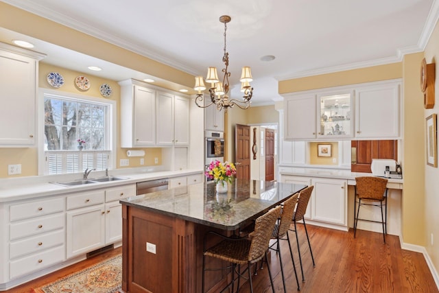 kitchen with sink, a breakfast bar, white cabinets, and a center island