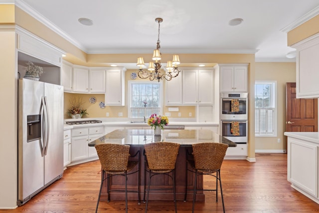 kitchen with white cabinetry, stainless steel appliances, a center island, and light hardwood / wood-style floors