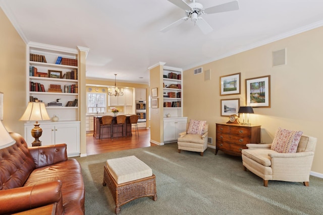 living room featuring crown molding, ceiling fan with notable chandelier, and carpet