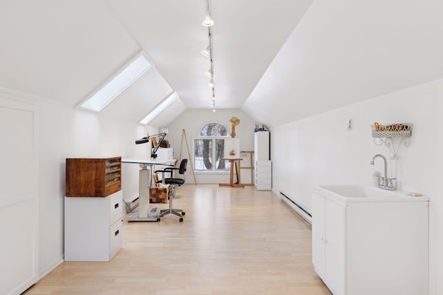 office with sink, rail lighting, lofted ceiling with skylight, light hardwood / wood-style floors, and a baseboard radiator