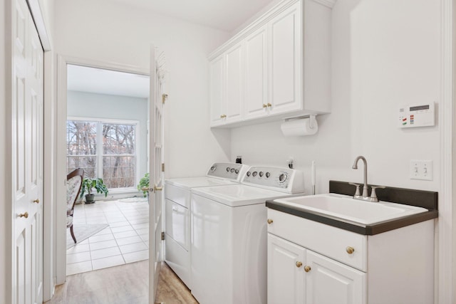 laundry room featuring cabinets, light hardwood / wood-style floors, sink, and washer and dryer