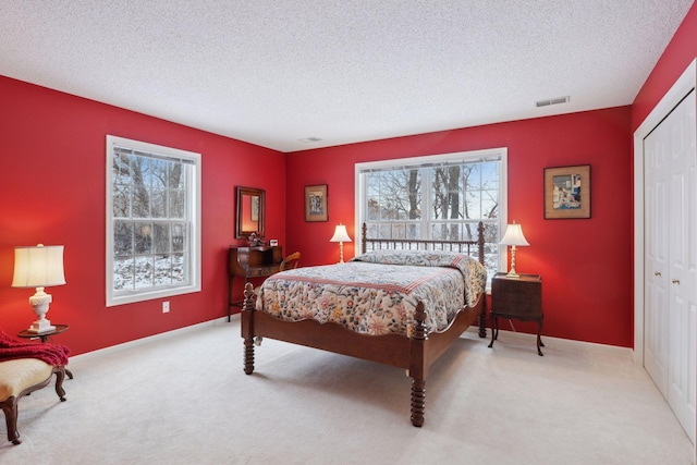 bedroom featuring light colored carpet, a textured ceiling, and a closet