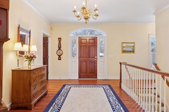 foyer with crown molding, wood-type flooring, and a chandelier