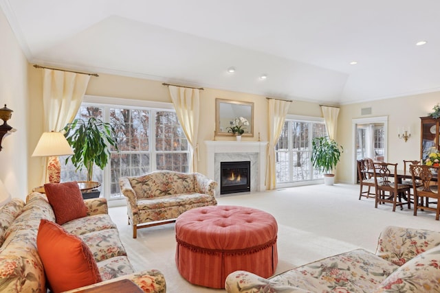 carpeted living room with a premium fireplace, vaulted ceiling, and ornamental molding