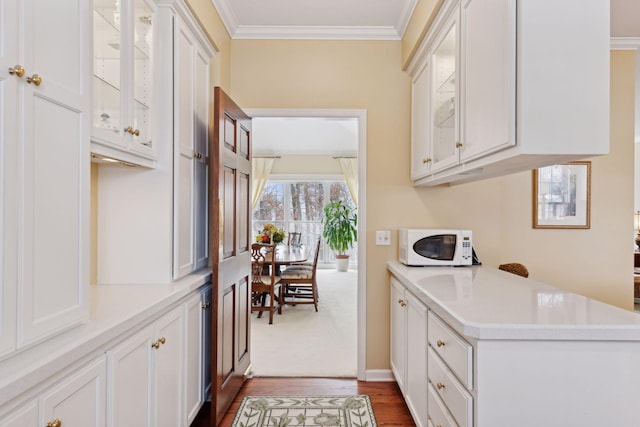 kitchen with white cabinetry, dark wood-type flooring, and crown molding