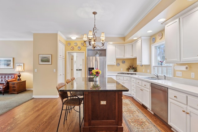 kitchen featuring a kitchen island, white cabinetry, appliances with stainless steel finishes, and a breakfast bar area