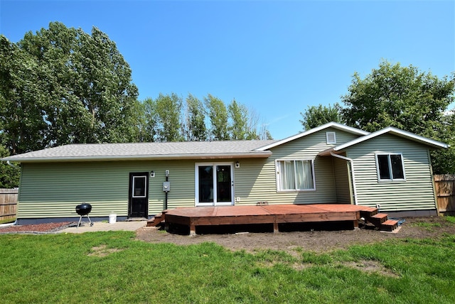 back of property featuring a wooden deck and a lawn