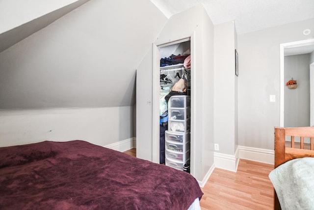 bedroom with a closet, light hardwood / wood-style flooring, and vaulted ceiling