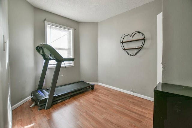 exercise area with a textured ceiling and light wood-type flooring