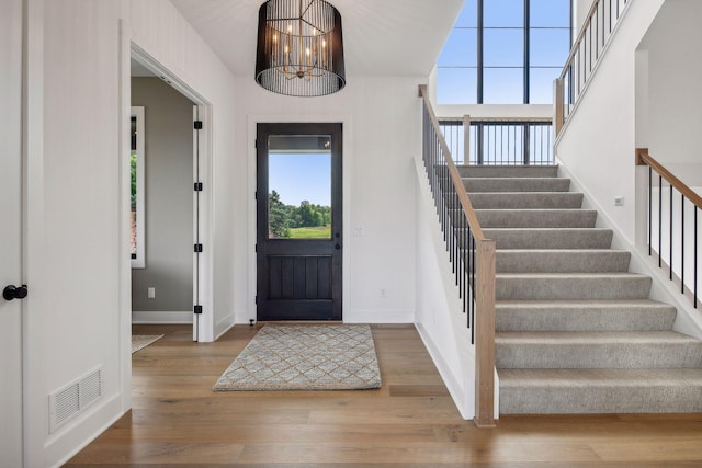 foyer with an inviting chandelier, hardwood / wood-style flooring, and a healthy amount of sunlight