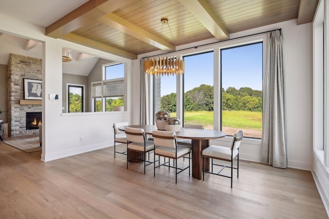 dining space with light hardwood / wood-style flooring, lofted ceiling with beams, wooden ceiling, and a fireplace