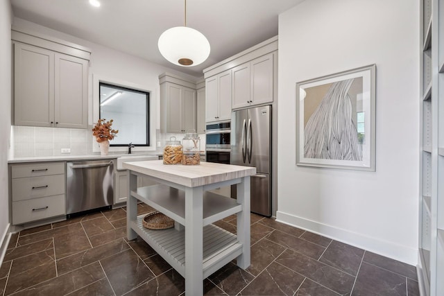 kitchen with tasteful backsplash, appliances with stainless steel finishes, sink, pendant lighting, and gray cabinets