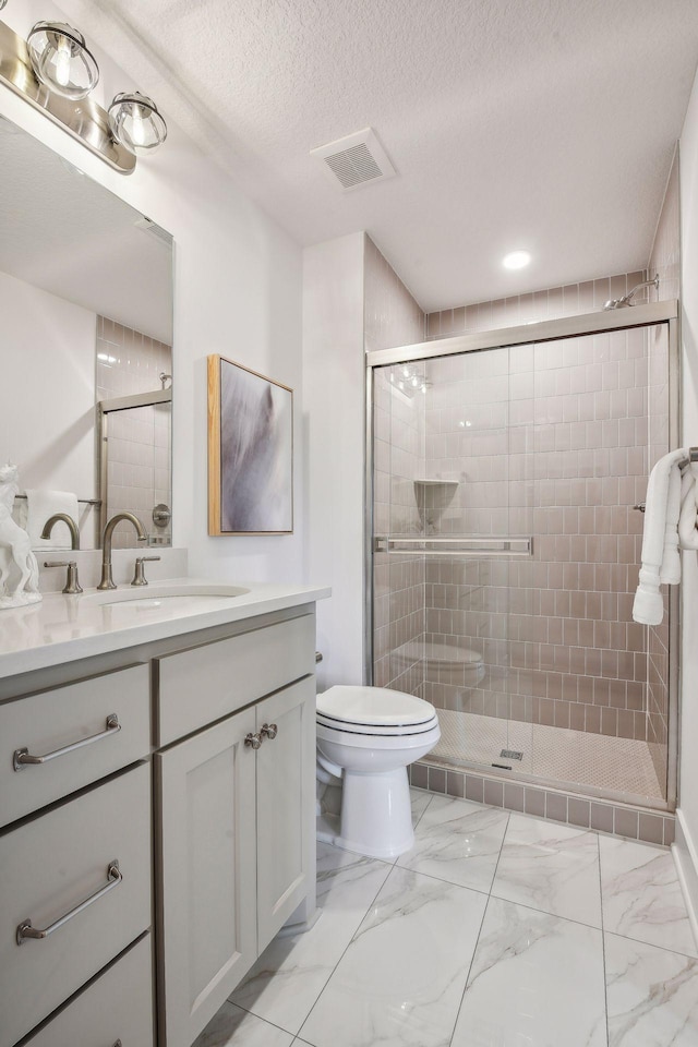 bathroom with vanity, toilet, a textured ceiling, and a shower with shower door