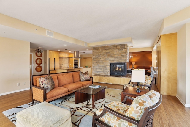 living room with light wood-type flooring and a stone fireplace