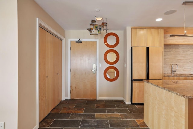 kitchen with decorative backsplash, light brown cabinetry, light stone countertops, and sink